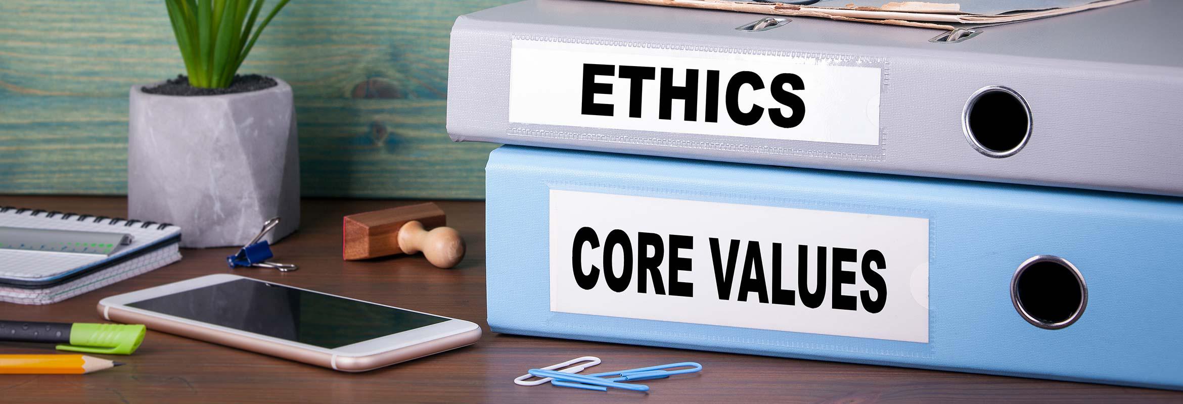 Image of a smartphone and binders with the words ethics and core values.